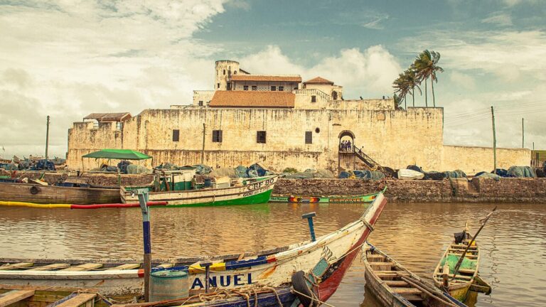 Colorful fishing boats in Elmina harbour, Ghana, under a bright coastal sky